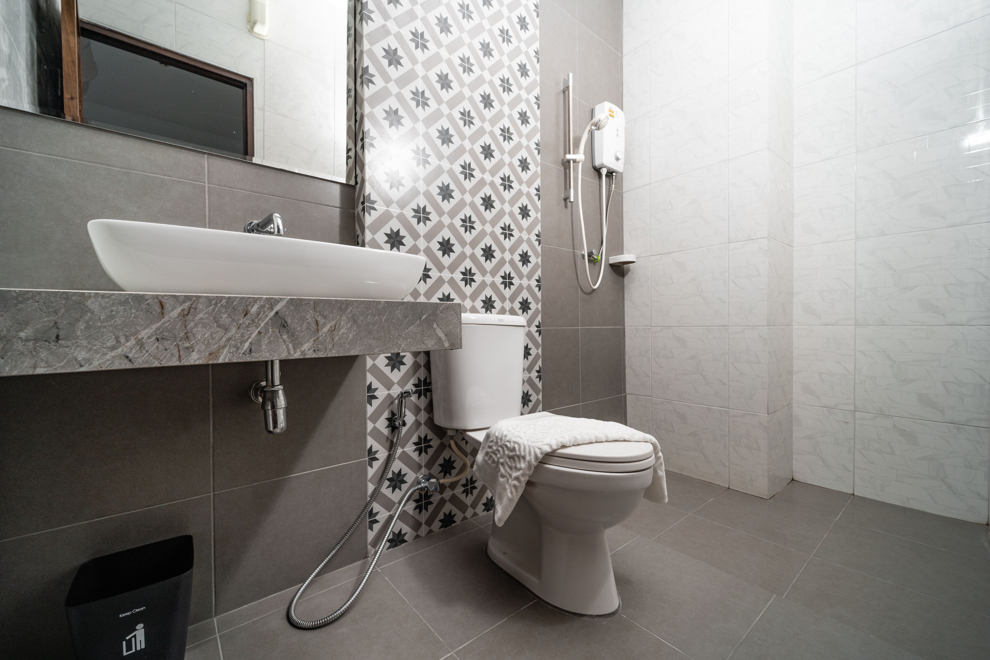 Een moderne badkamer met een wit wastafelmeubel, toilet en douche.