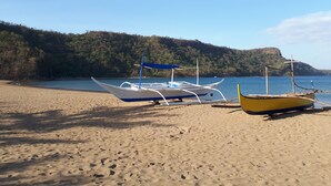 Una playa arenosa con dos barcos, uno azul y uno amarillo, amarrados cerca del agua.