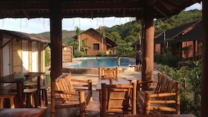 Un espacio de estar al aire libre con mobiliario de madera y una piscina.