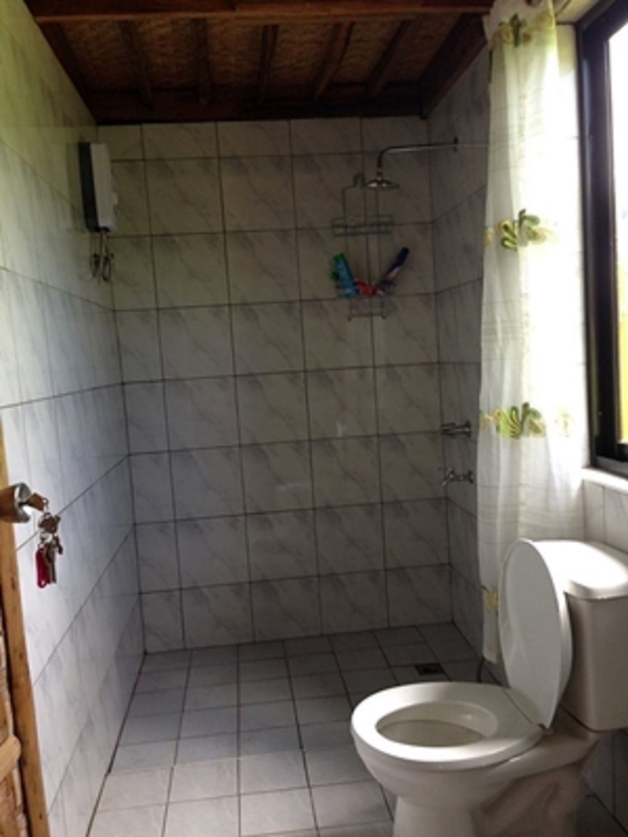 Une salle de bain avec des toilettes, une douche et des murs carrelés.
