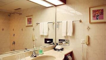 Un baño de hotel con un espejo grande, un lavamanos, un teléfono y varias toallas colgadas en un perchero.
