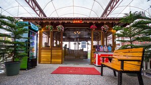 A covered entrance with a red mat, wooden benches, and potted plants. - Kea Garden Mini Chalet - Hostel (Brinchang)