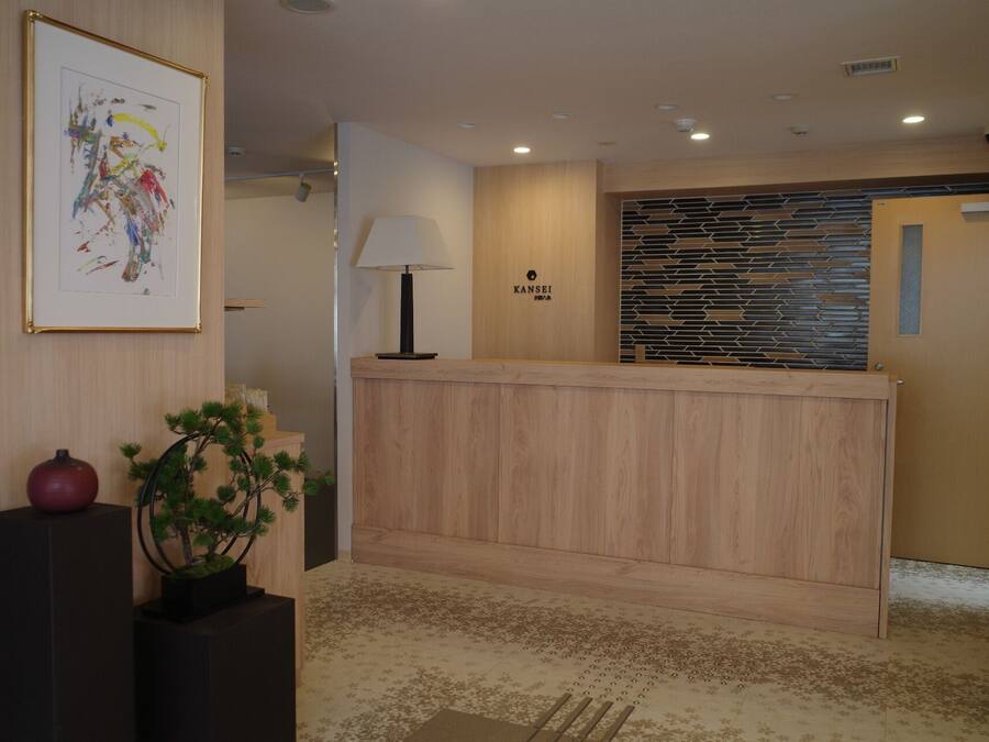 A reception desk with a modern design, a framed abstract painting, and a potted plant.