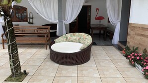 A cozy outdoor seating area with a wicker sofa, a wooden bench, and a small table. - Flamingo Beach Pousada (Cabo Frio)