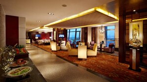 A hotel lobby with a buffet area, seating arrangements, and a large window offering a view.