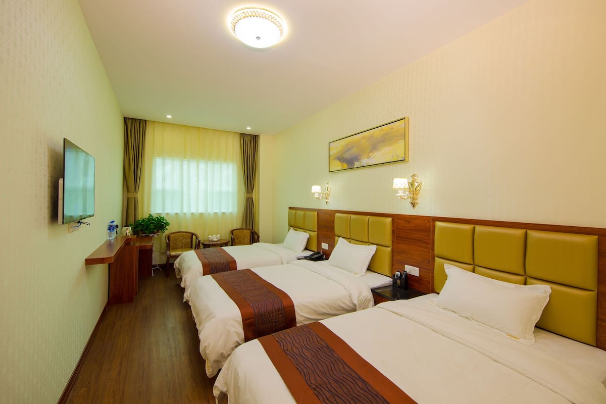A hotel room with two beds, a desk, a chair, a TV, and a window with curtains.