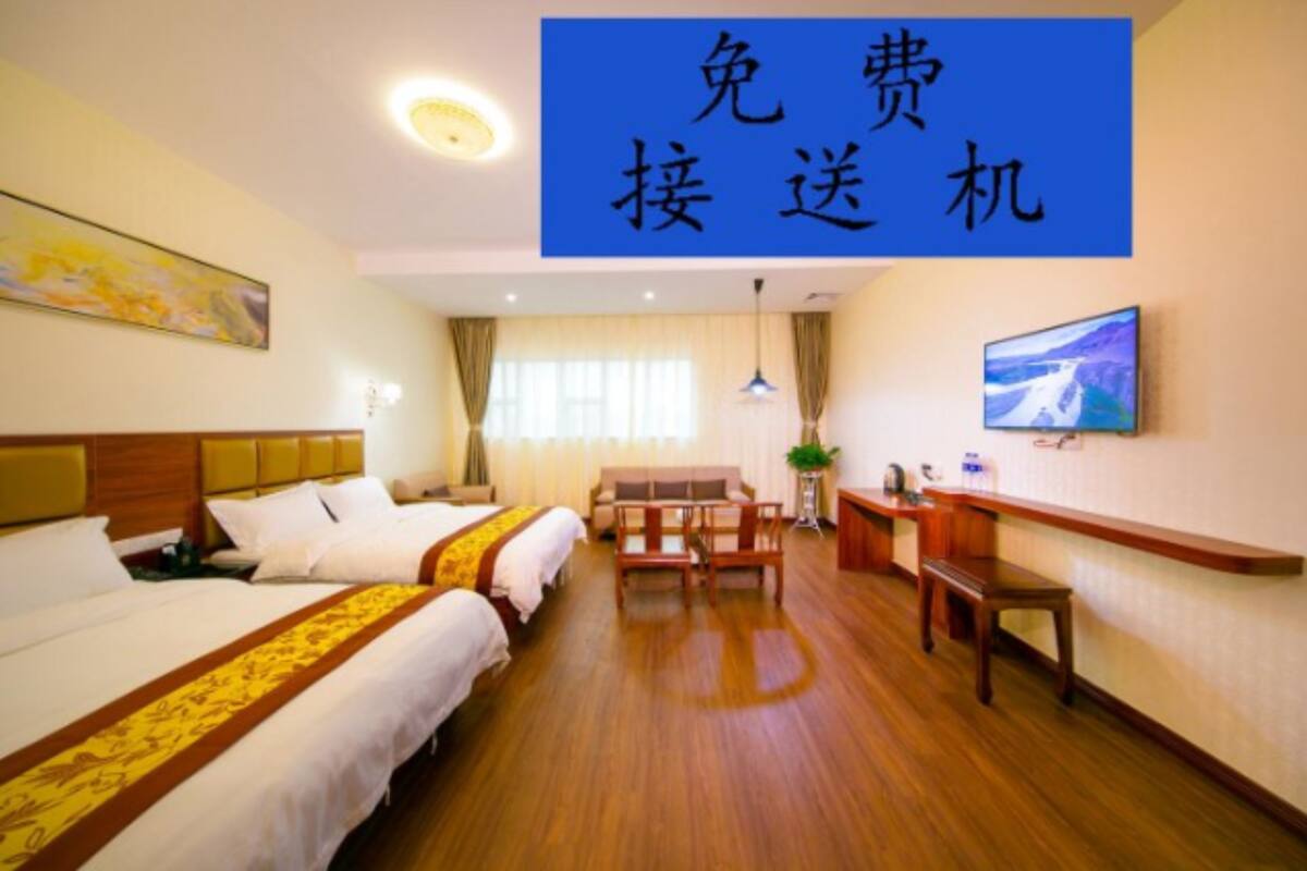 A hotel room with two beds, a desk, a chair, and a television on the wall.