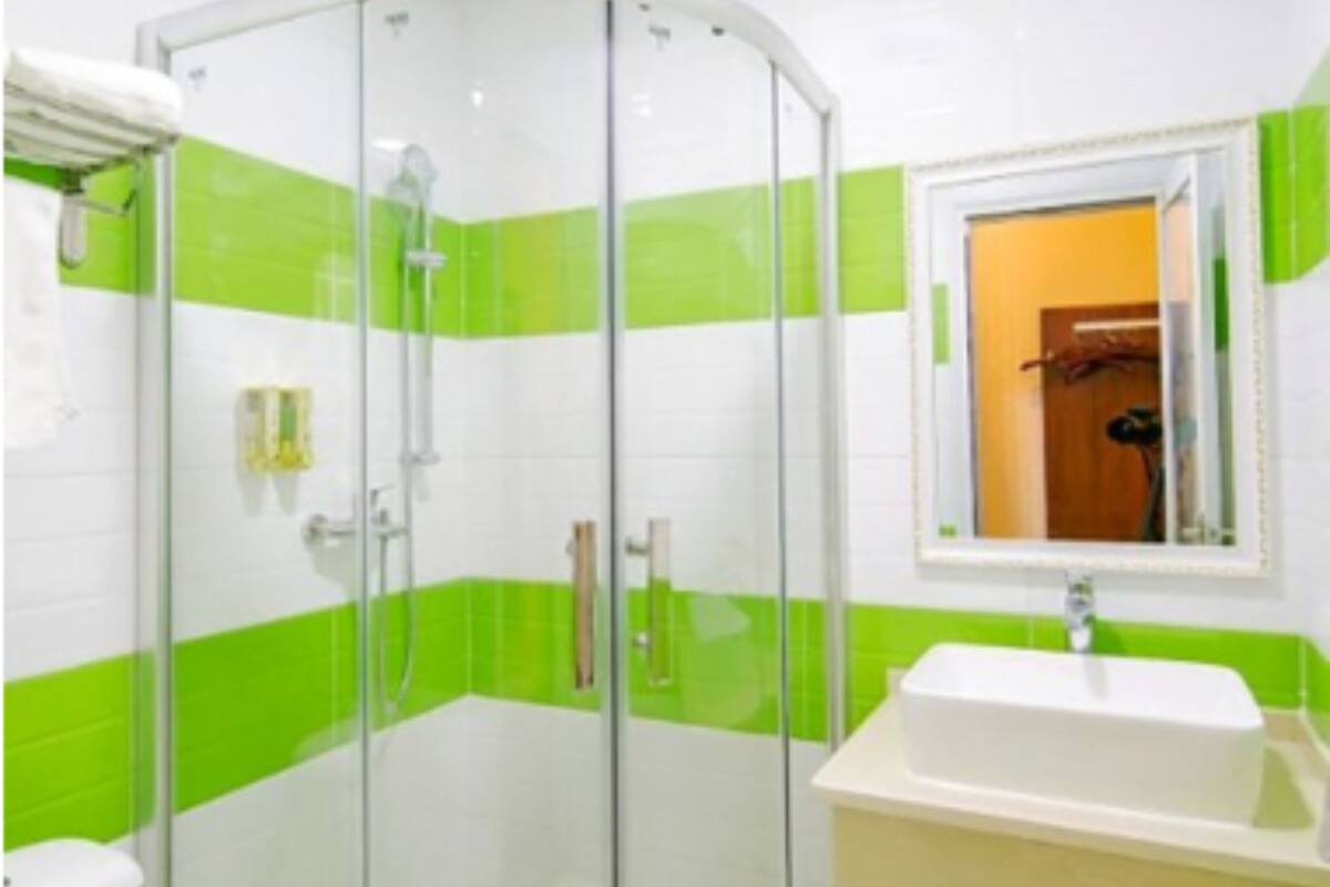 A bathroom with a glass-enclosed shower, a white sink, and a mirror above it.