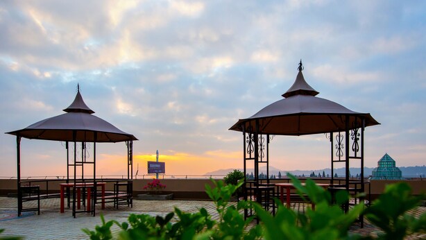 Two gazebos with metal frames and open roofs, a tiled floor, and a view of mountains in the background. - Yuehang Hotel (Zhuhai)