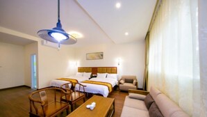 A hotel room with two beds, a sofa, a wooden table, and a ceiling light. - Yuehang Hotel (Zhuhai)