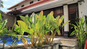 Un edificio con piscina y grandes plantas verdes al frente.