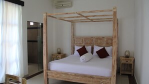Una cama con dosel de madera y ropa de cama blanca, flanqueada por dos mesitas de noche con adornos.