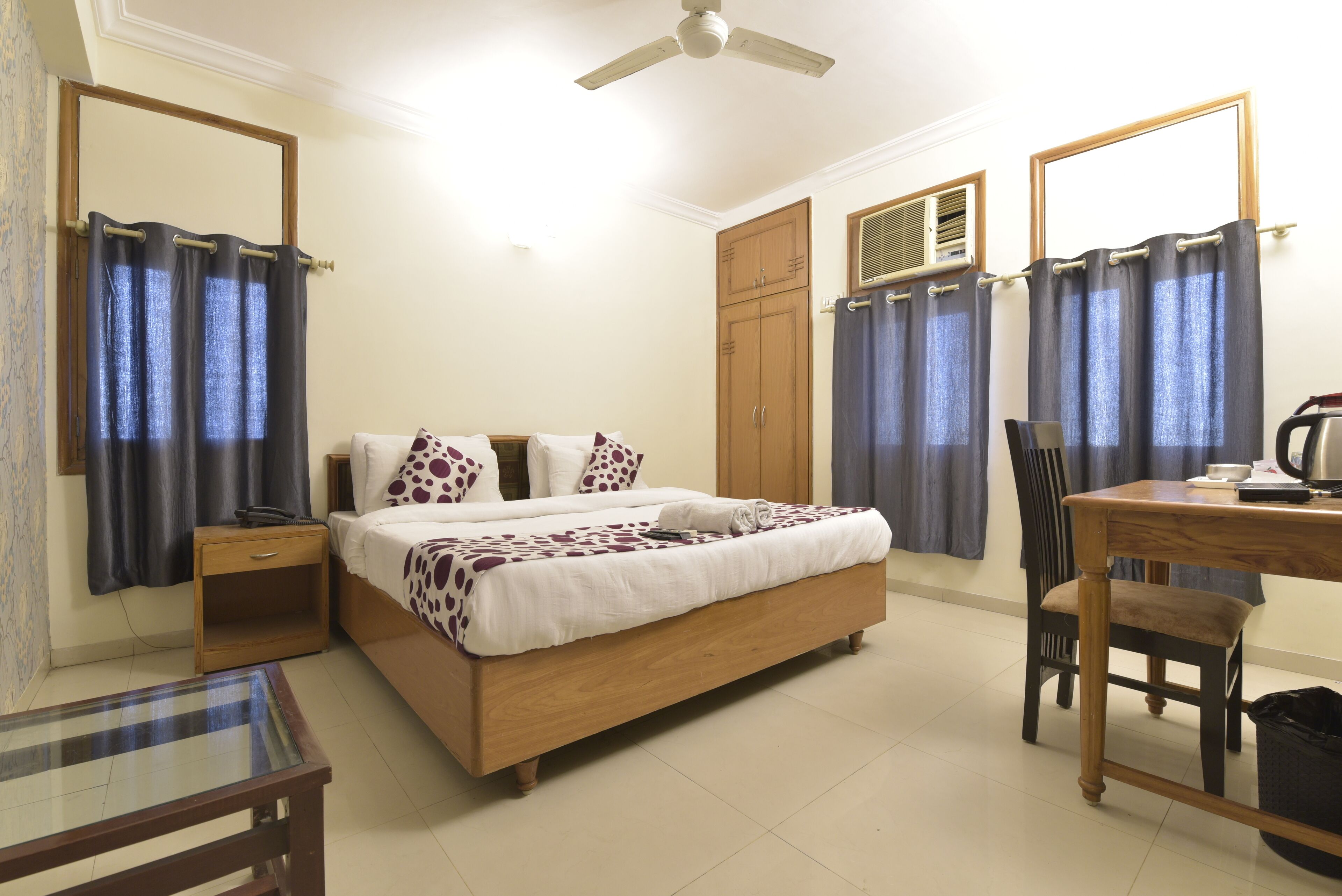 A bedroom with a bed, bedside table, chair, desk, and wardrobe.