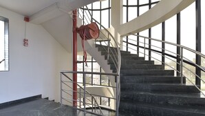 Un escalier avec des rampes en métal et un enrouleur de tuyau d’incendie rouge.