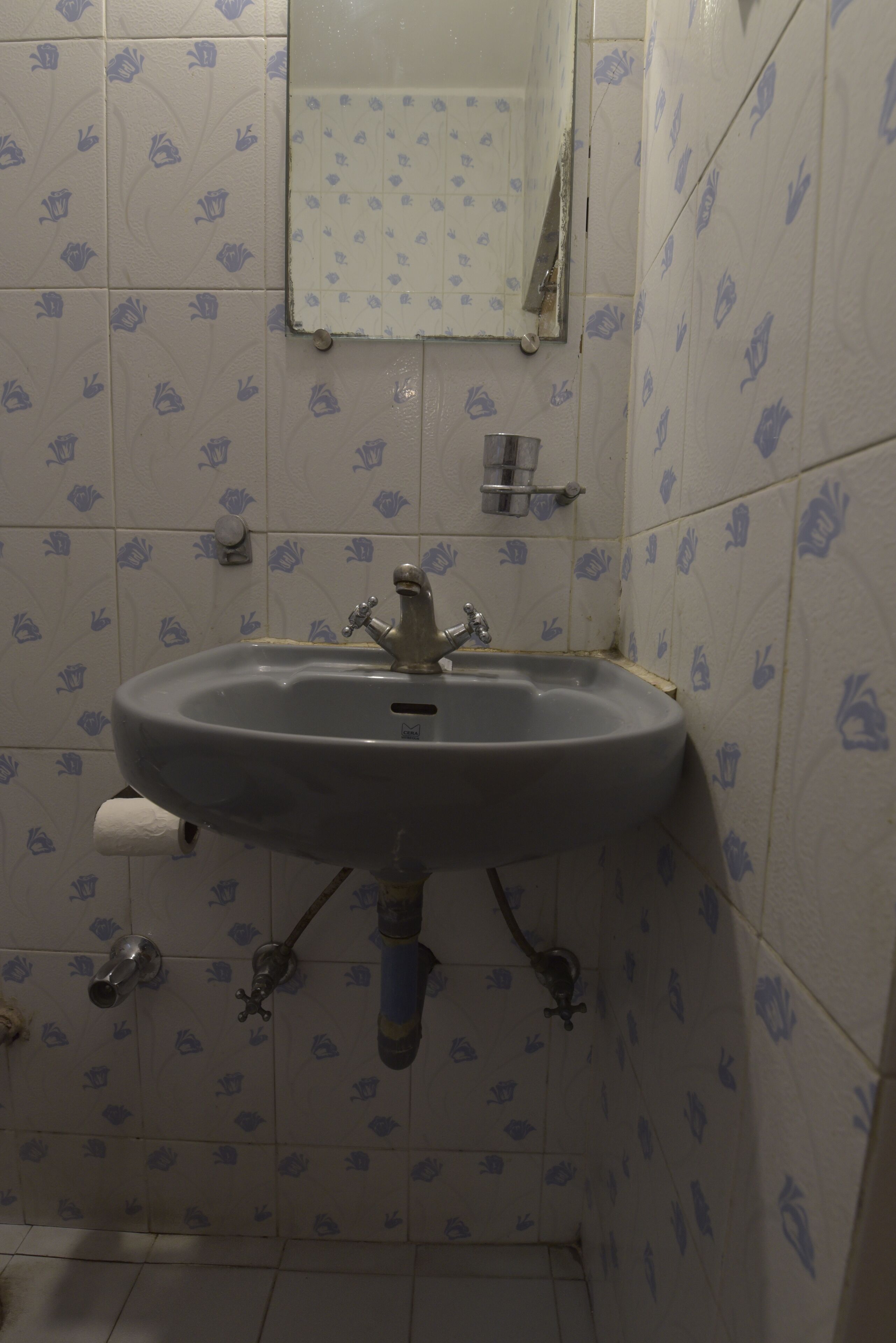 A bathroom with a sink, mirror, and tiled walls.