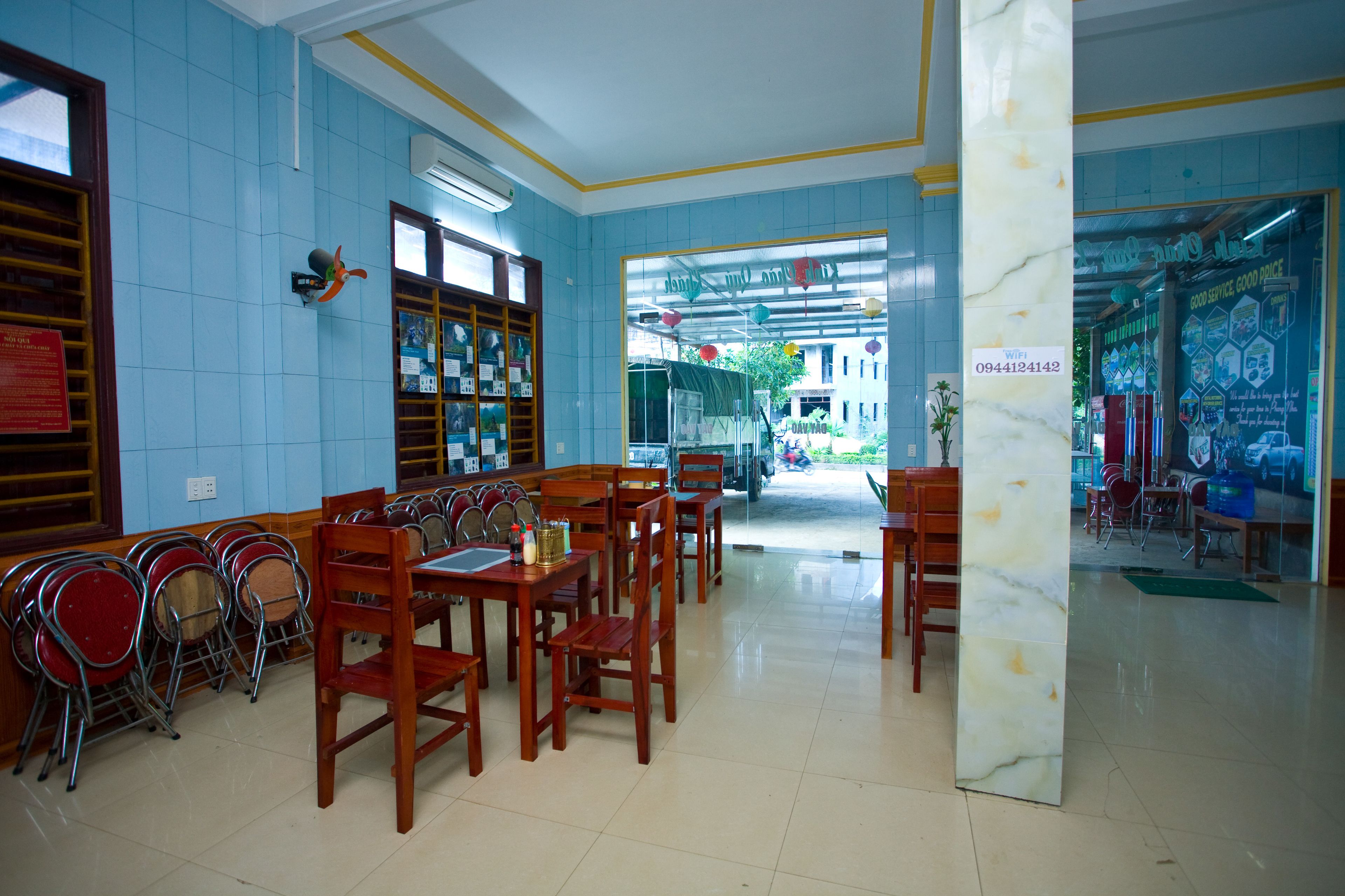 A restaurant with blue tiled walls, wooden tables and chairs, and a view of the street outside.