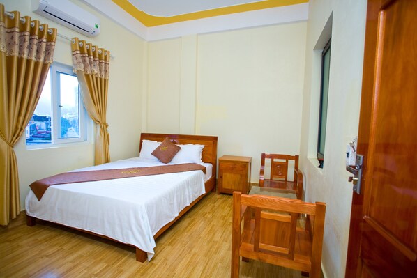 A hotel room with a bed, wooden nightstand, and a chair. - Co Cuc Hotel - Hostel (Phong Nha)