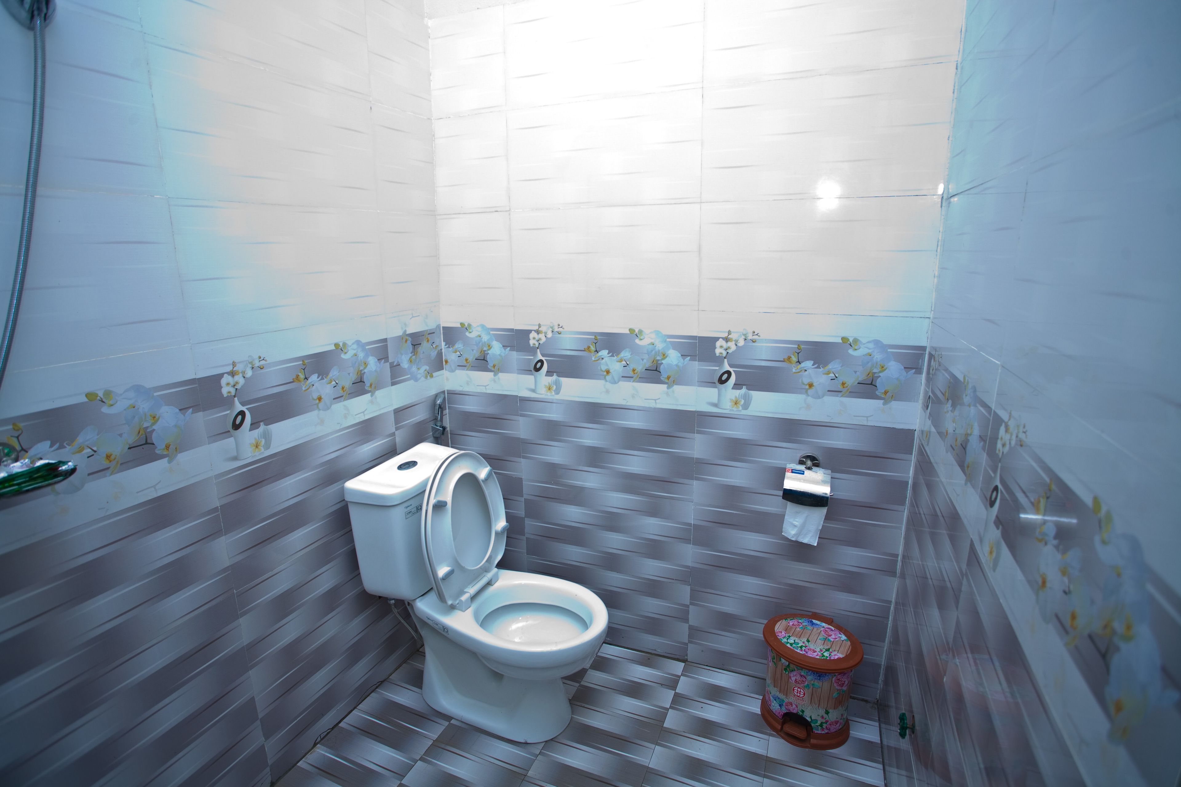 A bathroom with a toilet, a bidet, and a toilet paper holder.