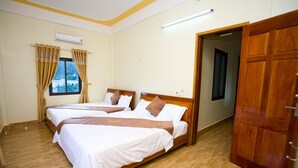 A hotel room with two beds, wooden flooring, a wooden door, and an air conditioning unit. - Co Cuc Hotel - Hostel (Phong Nha)