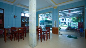 A spacious lobby with a marble column, wooden chairs, and a glass door leading outside. - Co Cuc Hotel - Hostel (Phong Nha)