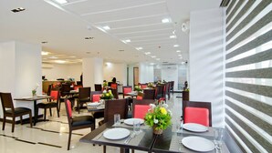A modern dining area with multiple tables and chairs, some with red cushions. - Tyche Boutique Hotel (Legazpi)