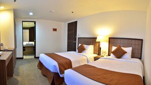 A hotel room with two beds, a desk, and a bathroom visible through an open door. - Tyche Boutique Hotel (Legazpi)
