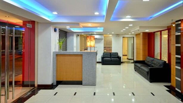 A modern lobby with a reception desk, black leather sofas, and a glass entrance. - Tyche Boutique Hotel (Legazpi)