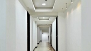 A long, narrow hallway with a tiled floor and white walls. - Tyche Boutique Hotel (Legazpi)