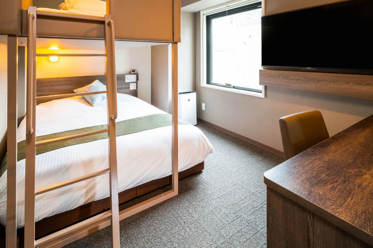 Una cama literera con escalera, un televisor de pantalla plana, un escritorio y una ventana con vistas.