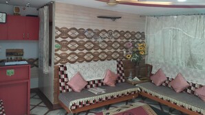 A living room with a sofa set, a red cabinet, a patterned wall, and a ceiling fan. - Airport Sky Inn (Jaipur)