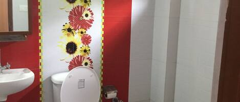 A bathroom with a toilet, sink, and a shower area.