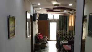 A hallway with a tiled floor, a seating area with chairs and a table, and a door leading to another room. - Airport Sky Inn (Jaipur)