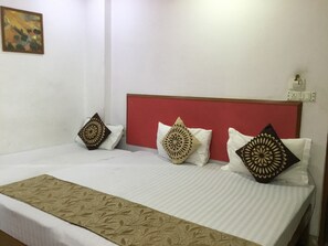 A neatly made bed with patterned pillows and a decorative bed runner.