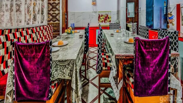 A dining area with a long table, patterned chairs, and a ceiling fan. - Airport Sky Inn (Jaipur)
