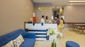 A reception area with a blue sofa, a reception desk, and a sign that reads "Oressund Hotel". - Oressund Hotel (Nha Trang)