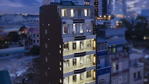 A multi-story building with balconies, a rooftop water tank, and a ground-level entrance. - Oressund Hotel (Nha Trang)