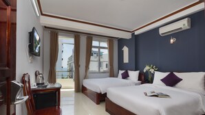 A hotel room with two beds, a TV mounted on the wall, a desk with a chair, and an air conditioning unit. - Oressund Hotel (Nha Trang)