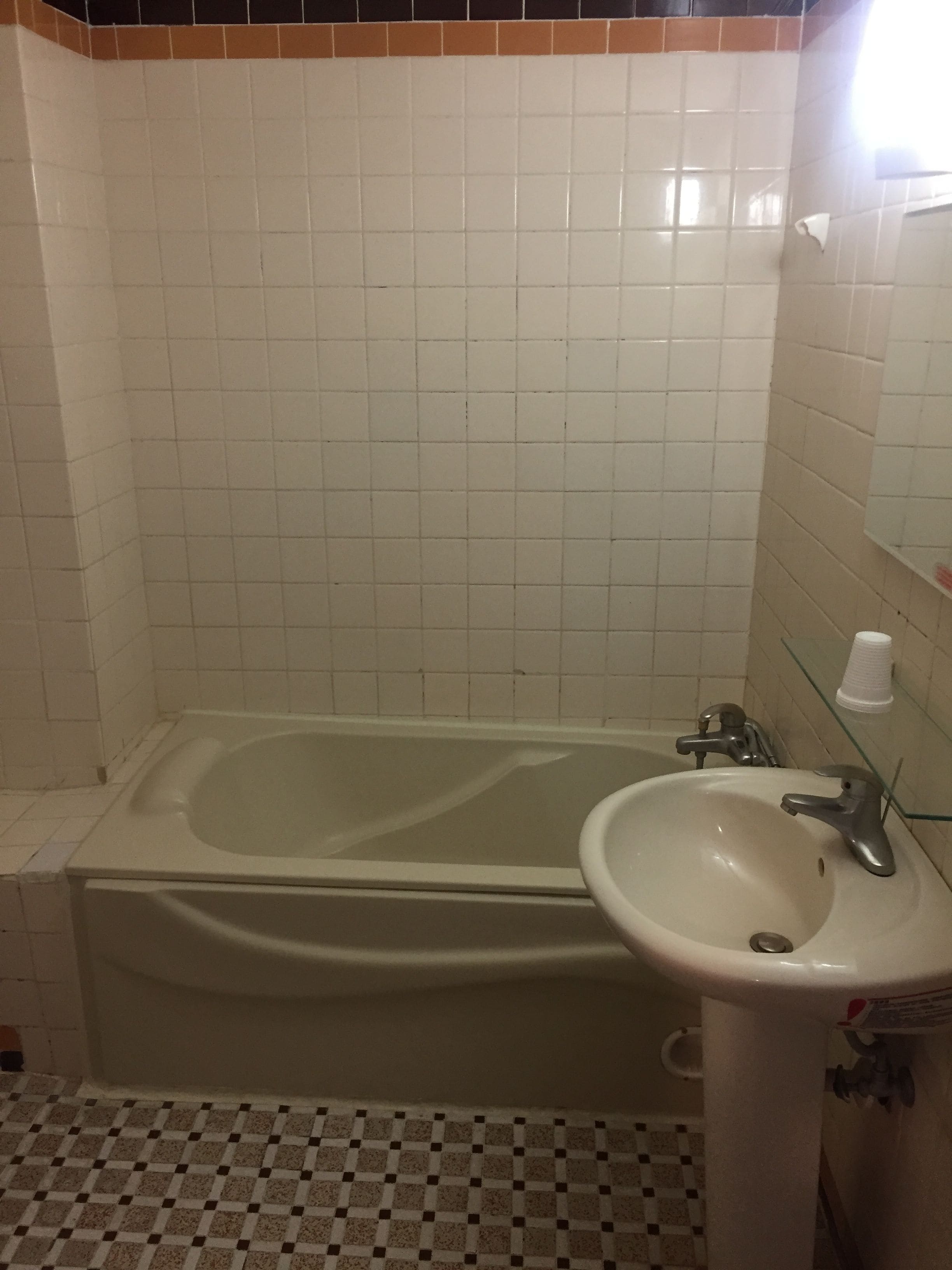 A bathroom with a bathtub, a sink, and a mirror.