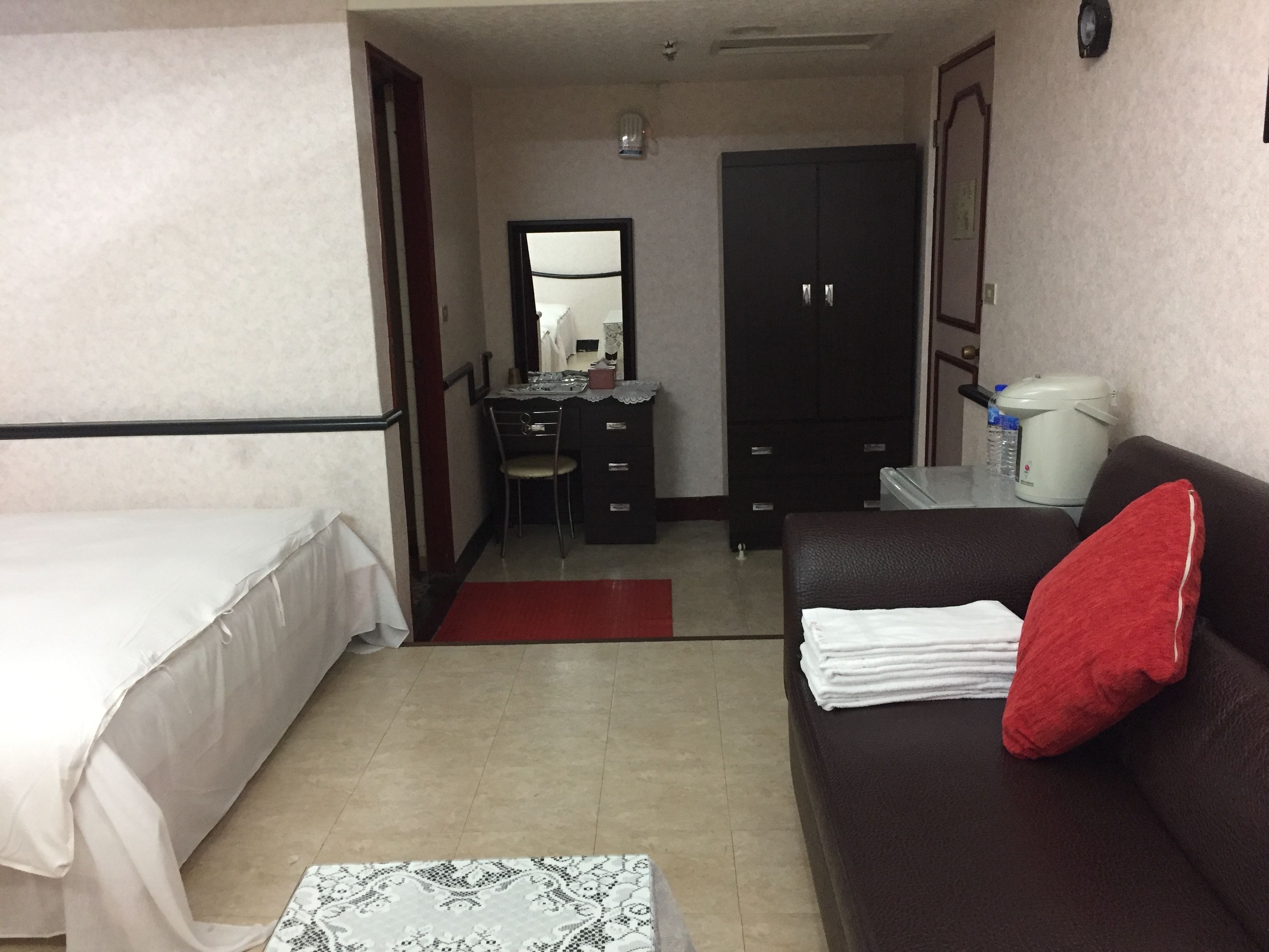 Habitación de hotel con cama, escritorio, silla, armario, sofá y cafetera.