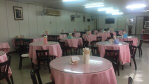 A dining area with round tables covered in pink tablecloths, arranged in rows with chairs. - King Lo Tung Hotel (Luodong)