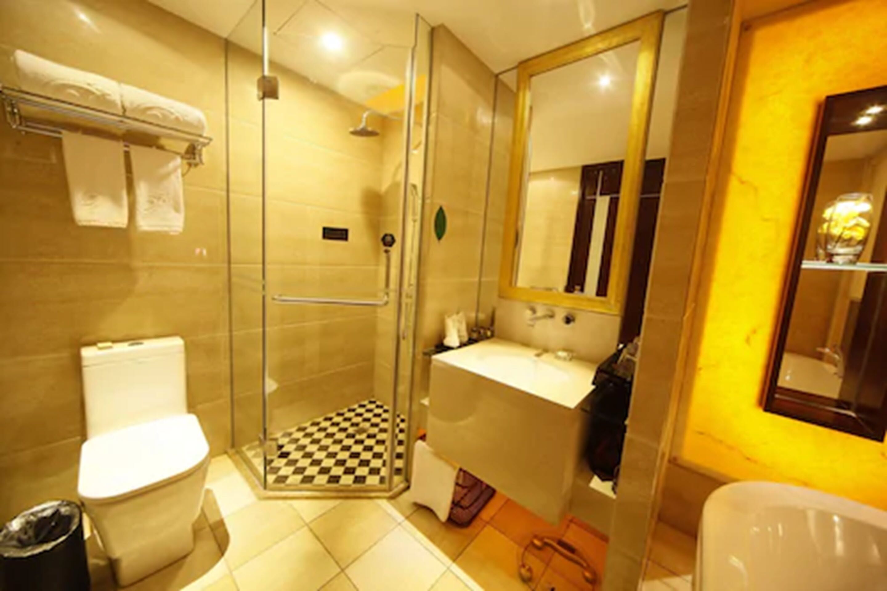 A bathroom with a glass-enclosed shower, a toilet, a sink, and a mirror.