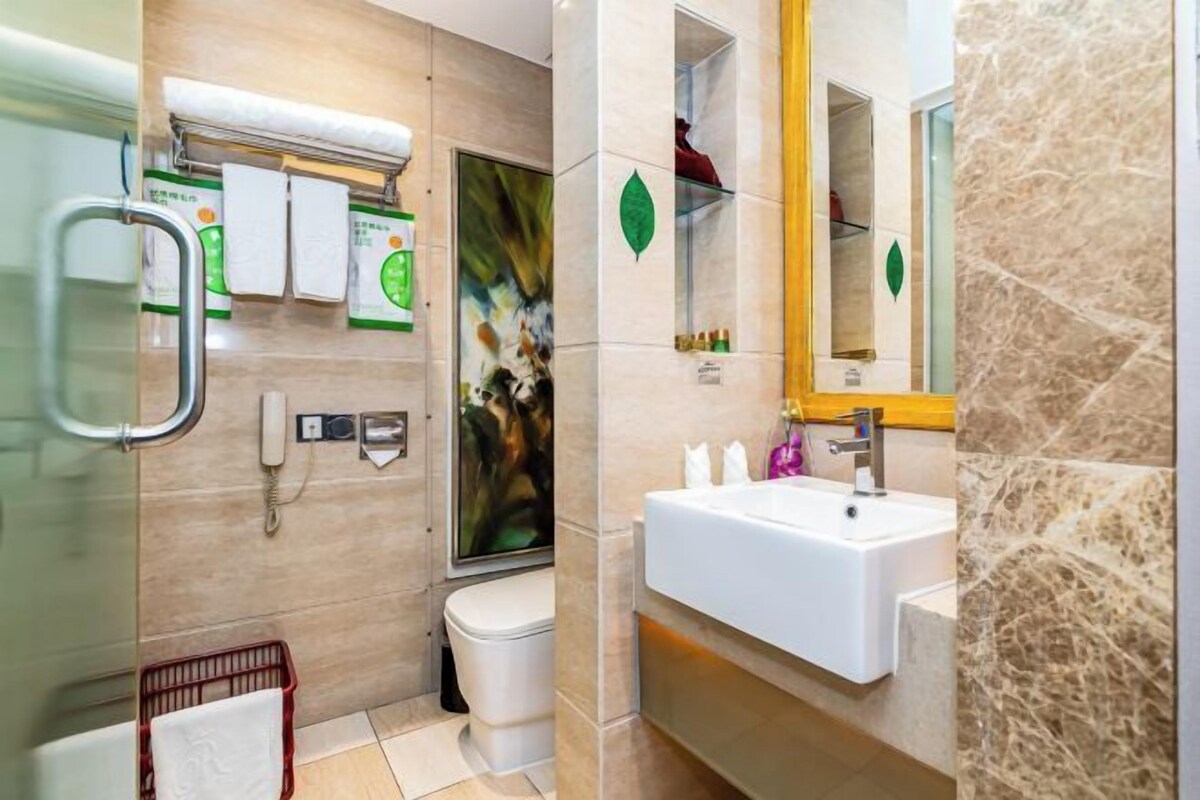 Une salle de bain moderne avec une douche à l’italienne en verre, un lavabo blanc et un mur en marbre.