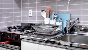 Una cocina con estufa a gas, un lavamanos y una tabla de cortar azul.