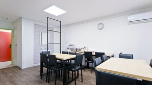 Un espacio de oficina moderno con una mesa de reuniones, sillas, un reloj y un equipo de aire acondicionado.
