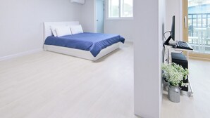 Un dormitorio moderno con una cama, un escritorio con una computadora y una ventana.