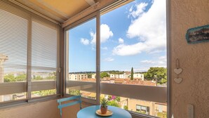 A balcony with a table and chairs, a potted plant, and a view of buildings and trees. - Cosy apartment for 4 people with A/C, WIFI, TV and terrace (Sanary-sur-mer)