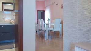 A modern dining area with a wooden floor, white chairs, and a white table. - Lovely apartment for 6 guests with A/C, WIFI, TV, terrace and pets allowed (Peroj)