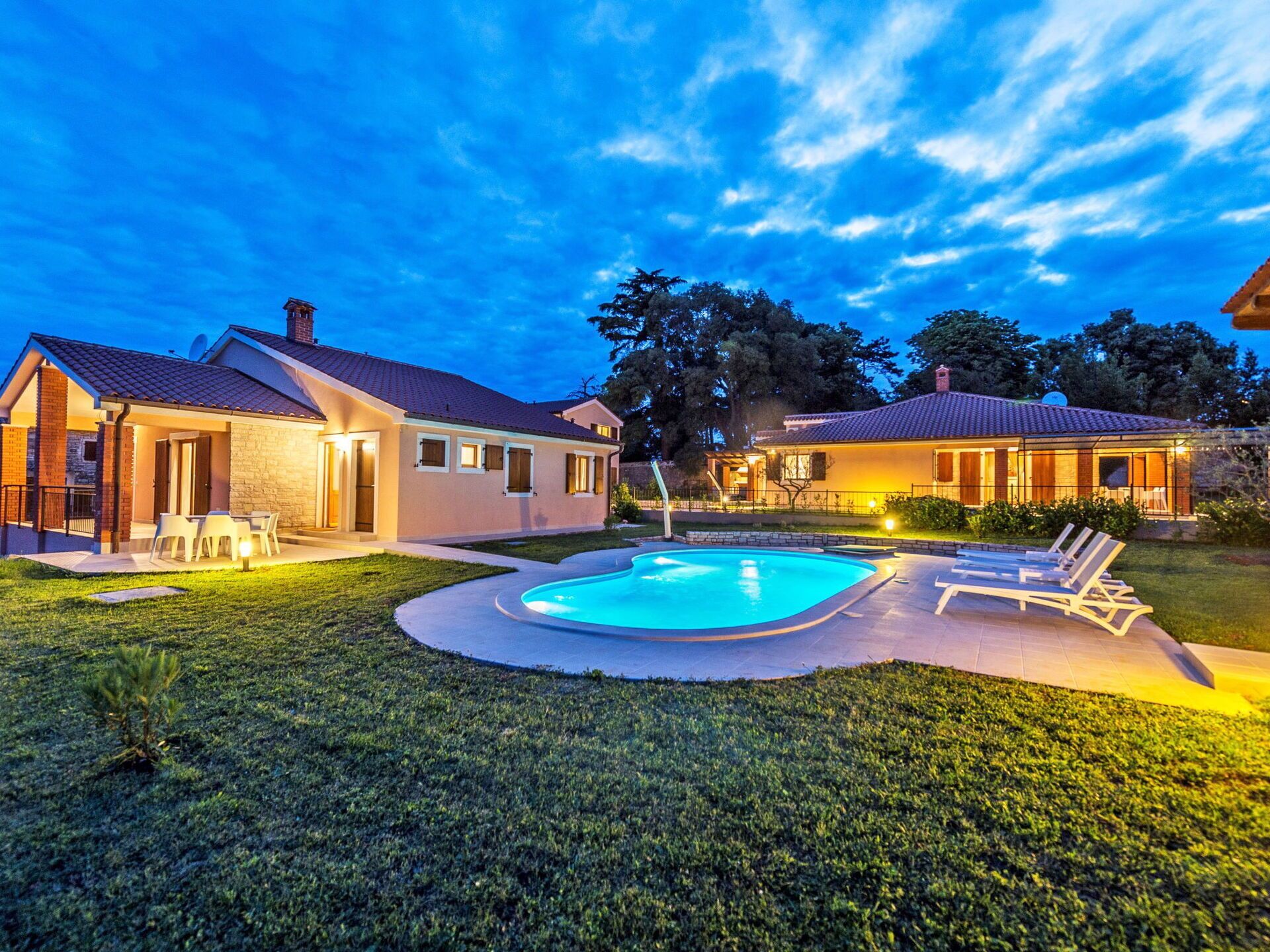 Una propiedad residencial con piscina, mobiliario de exterior y césped bien cuidado.