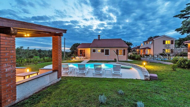 Una propiedad residencial con piscina, mobiliario de exterior y un césped bien cuidado.
