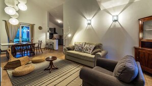 Una sala de estar moderna con sofá, sillón y comedor con mesa y sillas.